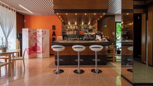A bar area with three stools, a counter with bottles, and a decorative wall with a 'BAR' sign. - Albergo Villa Gaia (Chianciano Terme)