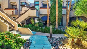 A modern building with multiple balconies, a central staircase, and a landscaped courtyard with palm trees and shrubs. - Palm Springs Getaway - A Ryson Property (Palm Springs)