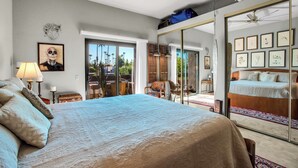 A bedroom with a large bed, a mirror, and a view of the outdoors. - Palm Springs Getaway - A Ryson Property (Palm Springs)
