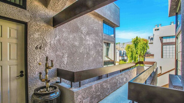 A modern building with a textured facade, a visible door, and a staircase leading to an upper level. - Palm Springs Getaway - A Ryson Property (Palm Springs)