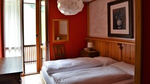 A room with a bed, a wooden nightstand, a mirror, and a hanging light fixture. - Hotel Cristallo (Folgaria)