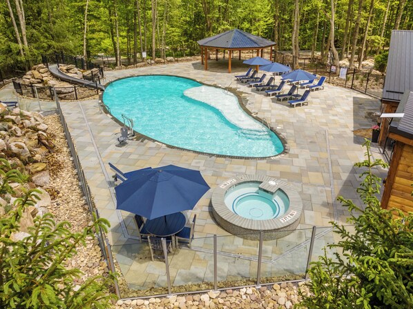 Un espace piscine comprenant un jacuzzi, des chaises longues et un kiosque.