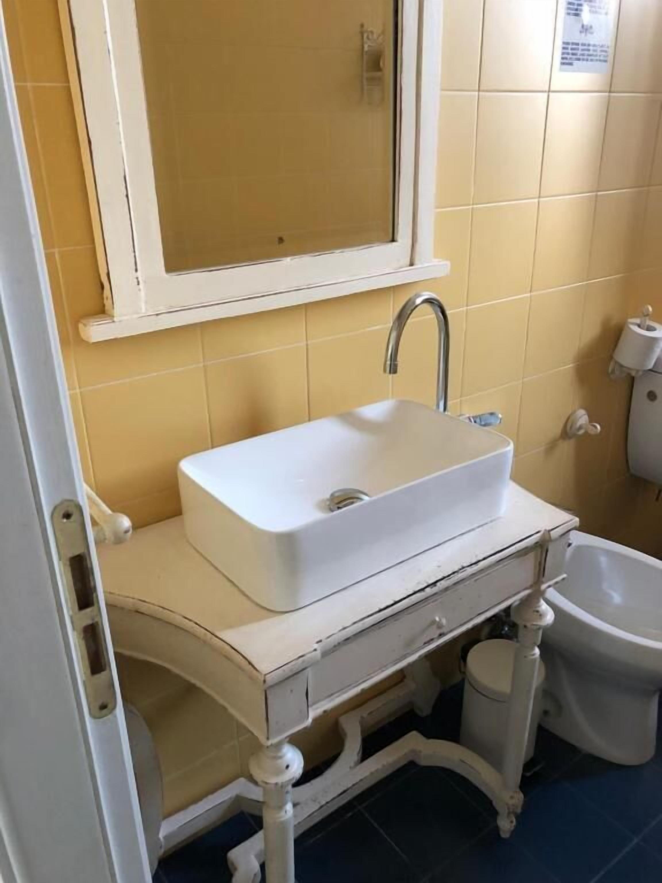 Un bany amb un lavabo blanc, un mirall a la part superior i un vàter.