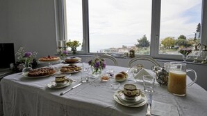 A table set for breakfast with pastries, tea, and a pitcher of juice, overlooking a scenic view. - Villa Giannina (Taormina)