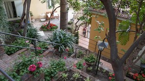 A garden with various plants and flowers, a staircase, and a yellow wall. - Villa Giannina (Taormina)