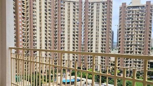A high-rise residential building with multiple balconies, a view of the surrounding area, and a clear sky. - Lux Studio Epic Stay (Gurugram)