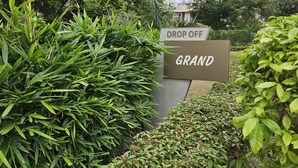 A sign with "DROP OFF" and "GRAND" indicating a location for drop-off services. - Lux Studio Epic Stay (Gurugram)