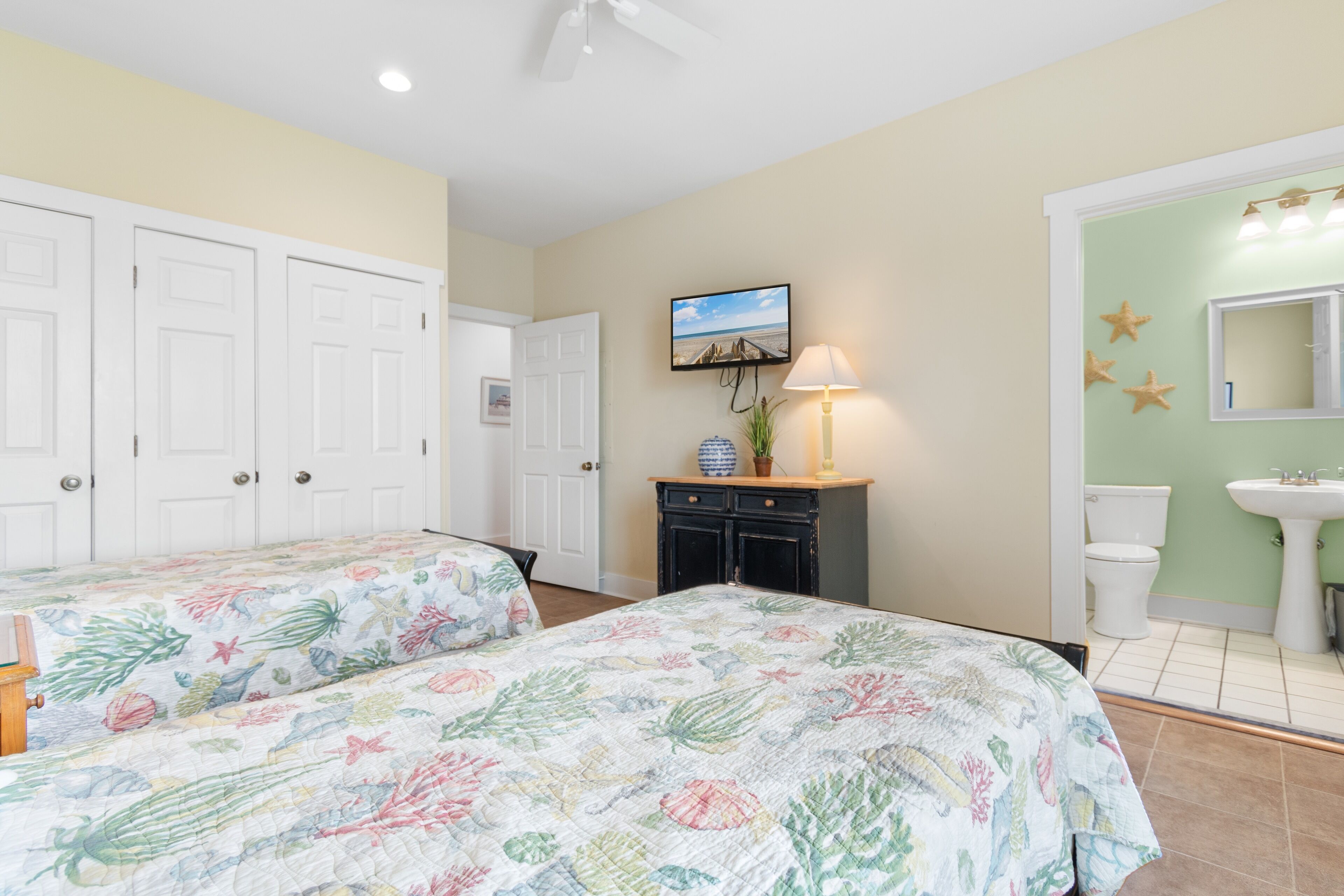 Unwind in your coastal bedroom with tropical bedding, wall-mounted TV, and convenient en-suite bathroom for ultimate comfort.