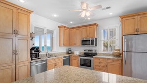 A kitchen with granite countertops, wooden cabinets, stainless steel appliances, and a ceiling fan. - 6-Bedroom Beach House w/ Private Dock & Pool in Inlet Harbour (Murrells Inlet)