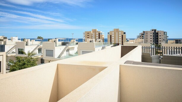 A rooftop terrace with a clear view of the sea and adjacent buildings.