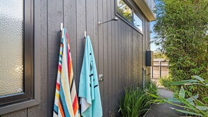 A wooden exterior wall with two towels hanging on hooks, a small window, and a pathway leading to a garden area. - Sublime Sanctuary: 4  BR, 2  BA House in Rye , Sleeps 14 (Rye)