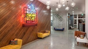 A modern lobby with a wooden wall, a neon sign, a bicycle mural, and a blue sofa. - Landing | Chic 1BD, Rooftop Lounge, Gym (Portland)