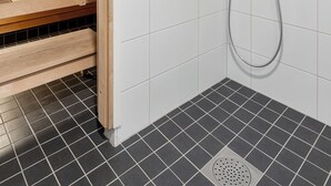 Ein Duschbereich mit Holzboden, einer Duschbrause und gefliestem Boden.