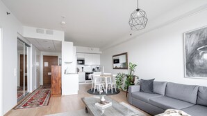 Ein modernes Wohnzimmer mit grauem Sofa, einem Couchtisch und einem Essbereich mit Holztisch und Stühlen.