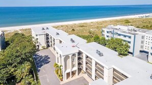 Un hotel frente a la playa con varias edificaciones, un estacionamiento y vista despejada del océano.