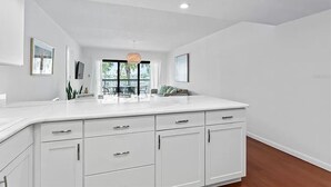Una cocina moderna con armarios blancos, una isla grande e iluminación colgante.