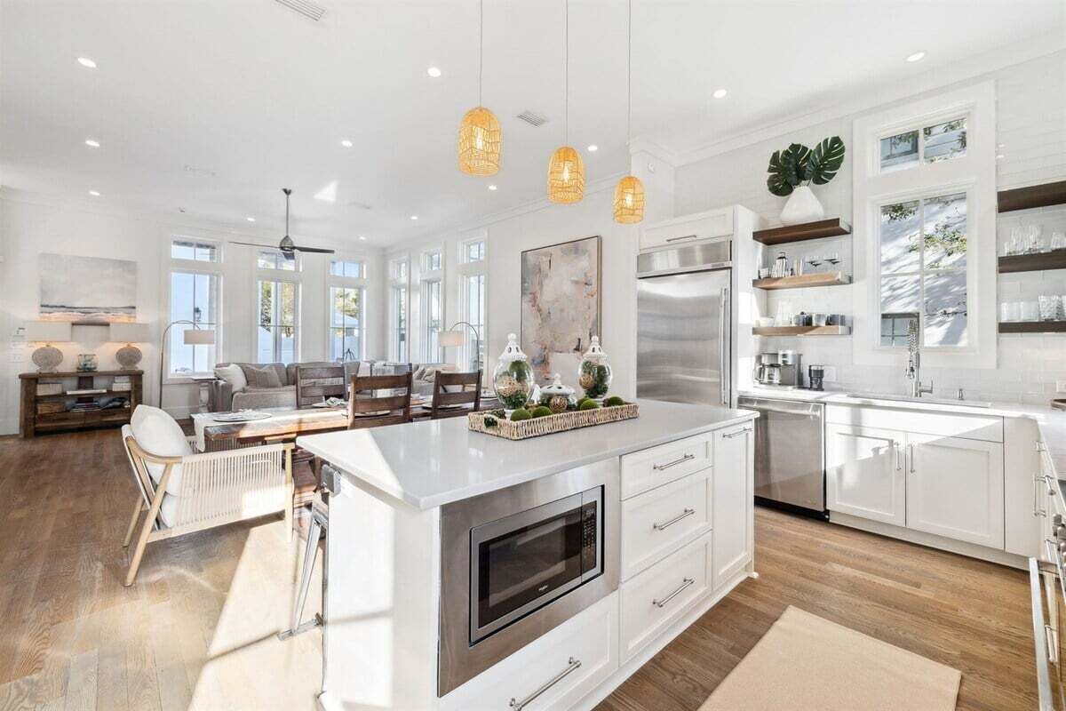A spacious kitchen with a large island, white cabinetry, and pendant lighting.
