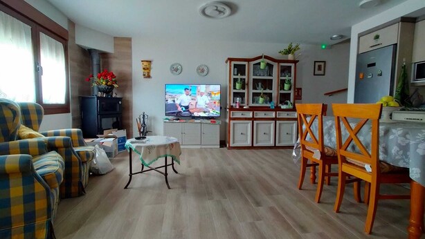 Un salon comprenant un canapé, une table à manger avec des chaises, un téléviseur et un meuble avec des portes en verre.