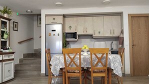 Une cuisine compacte avec un coin repas, comprenant un réfrigérateur, un four à micro-ondes et des armoires en bois.