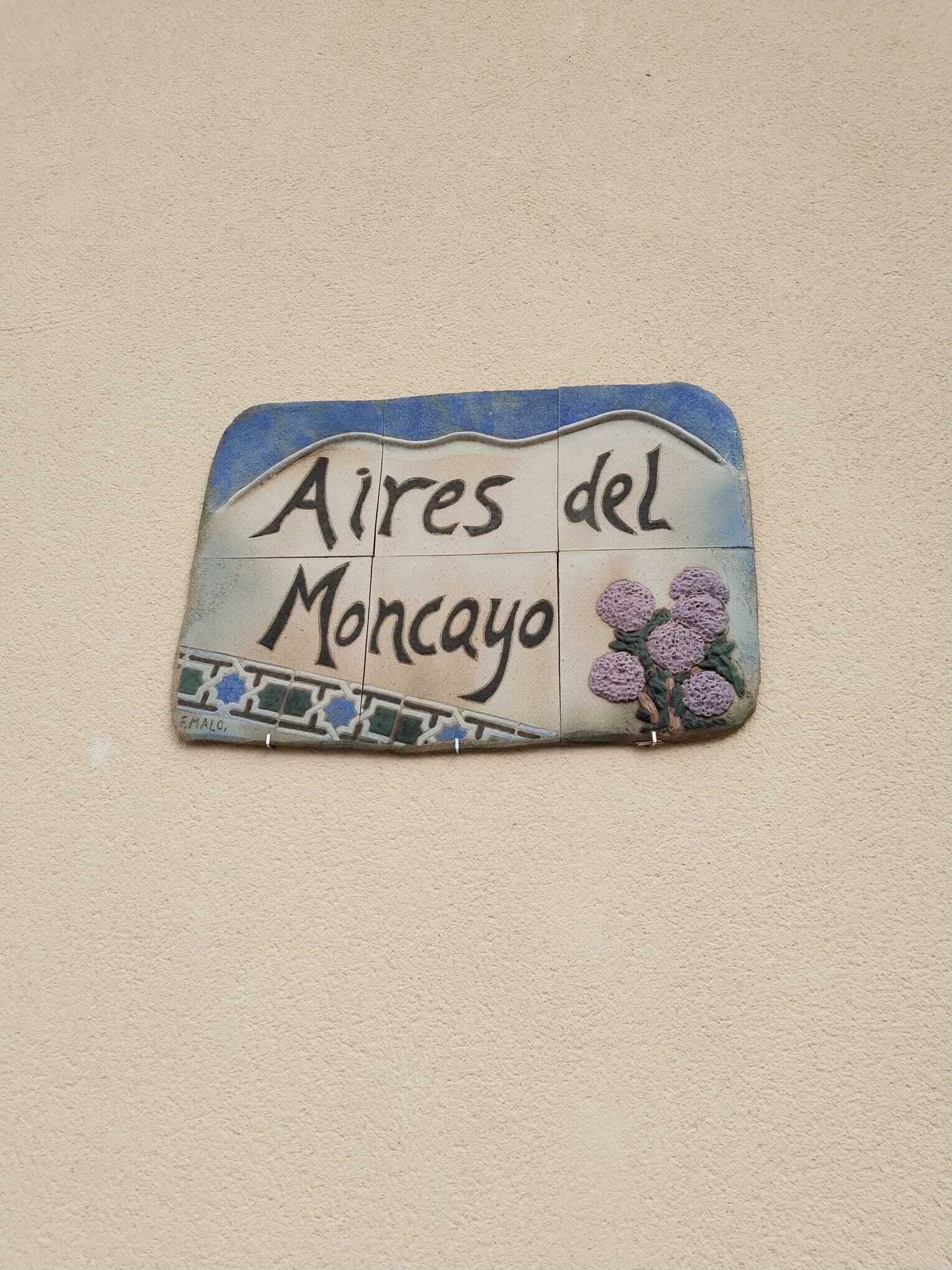 A wall-mounted sign with the text "Aires del Moncayo" and a decorative floral design.