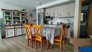 Une cuisine de taille réduite avec un coin repas, des meubles en bois et un four à micro-ondes.