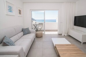 Relax in this ocean-view living room with a sofa, coffee table, and TV stand, perfect for unwinding in comfort.