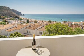 Enjoy a romantic meal on this balcony overlooking the sea and a charming coastal town.