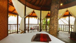 A room with a bed, a table with chairs, and a view of a natural landscape. - Rainforest  (Chalakudy)