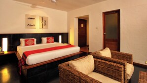 A hotel room with a large bed, two wall art pieces, a ceiling fan, and wicker furniture. - Rainforest  (Chalakudy)