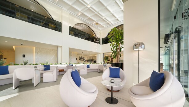 Un hall d’entrée spacieux, doté de sièges modernes, d’une grande plante et d’un mur en verre.