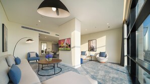Un salon moderne comprenant un canapé, des fauteuils, une table basse et un téléviseur.