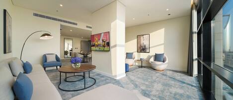 A modern living room with a sofa, armchairs, a coffee table, and a TV.