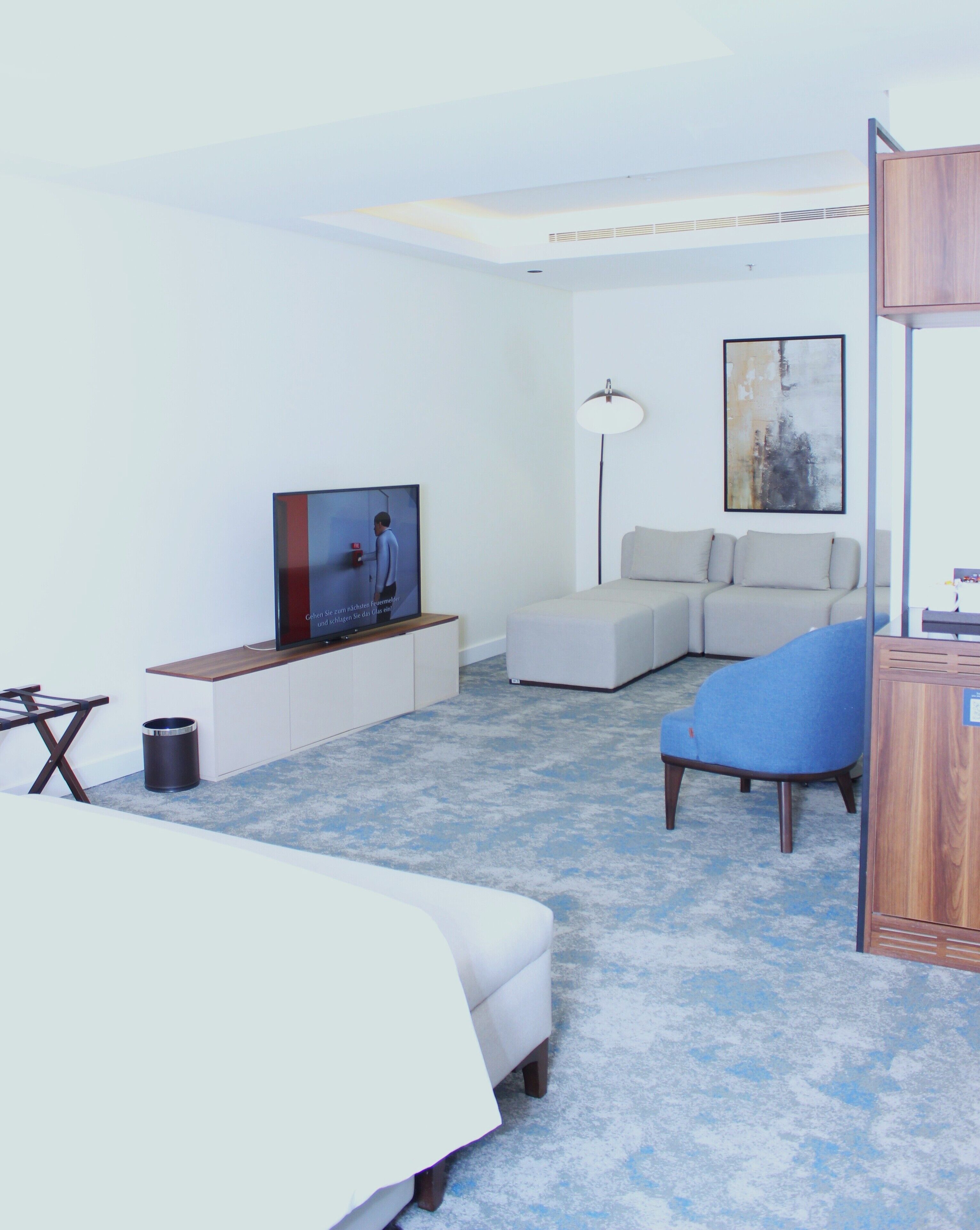 A modern hotel room with a bed, a sofa, a TV, and a desk.