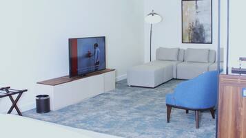 Une chambre d’hôtel moderne équipée d’un lit, d’un canapé, d’une télévision et d’un bureau.
