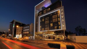 Un hôtel moderne, reconnaissable à son grand panneau « NOVOM », à ses larges fenêtres et à son hall d’entrée bien éclairé.