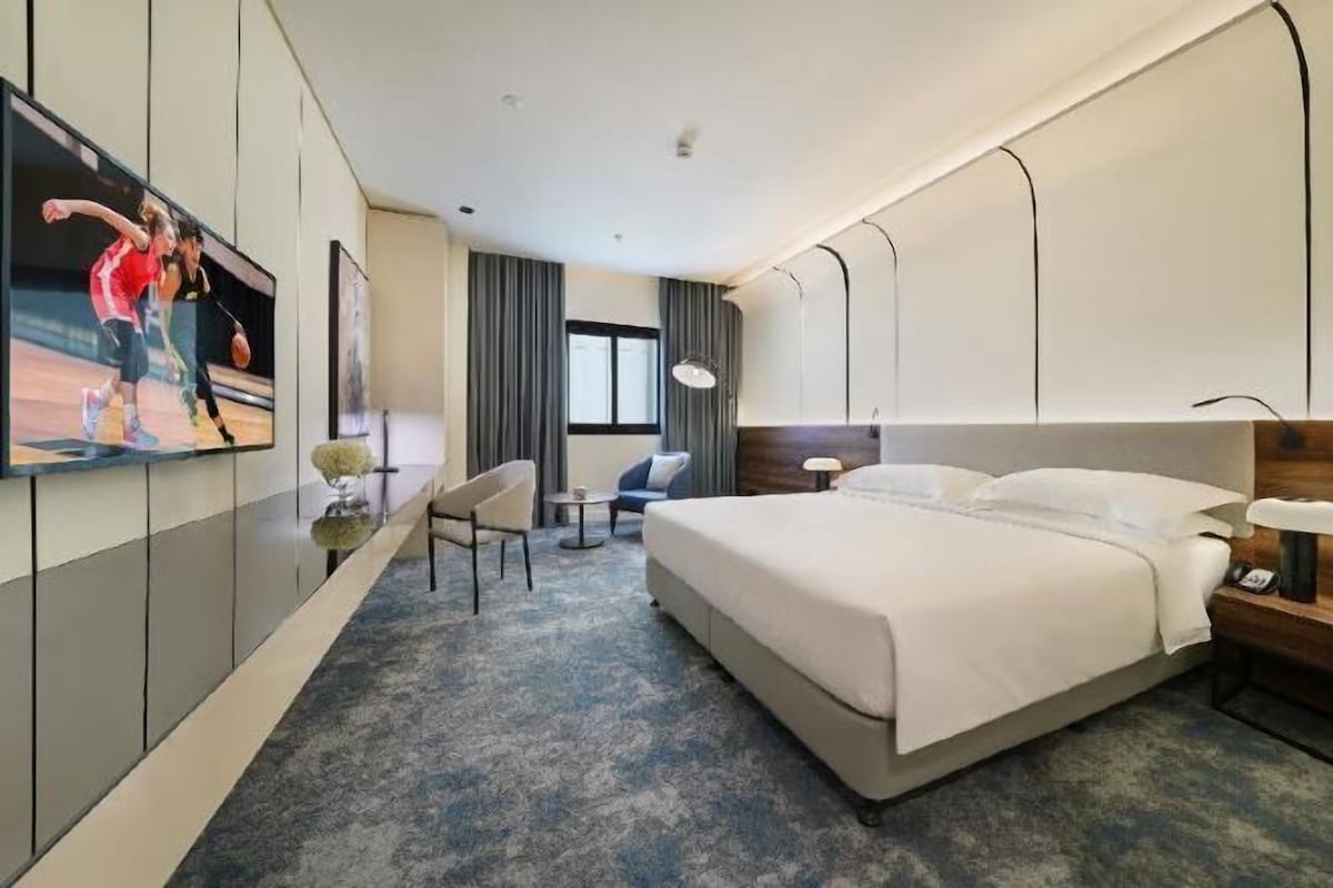 Une chambre d’hôtel avec un lit, une télévision, un bureau et une chaise.