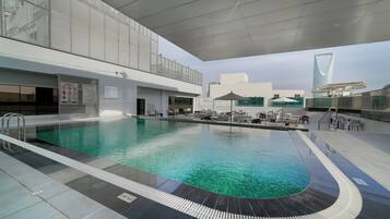 Alberca al aire libre, sombrillas en la alberca y camastros