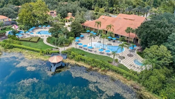 Un resort con varias piscinas, palmeras y vistas al bosque circundante.