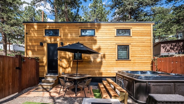 Een houten chalet met terras, een hottub en een vuurkuil.