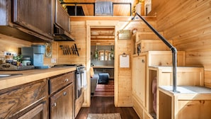 Een compact houten hutje met een kitchenette, een eethoek en een slaapzolder.
