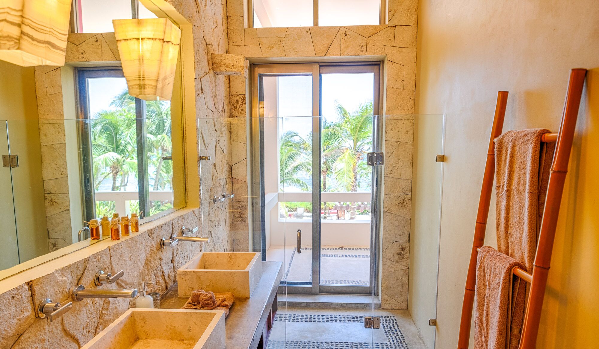 A bathroom with two sinks, a large mirror, and a glass door leading to a balcony.