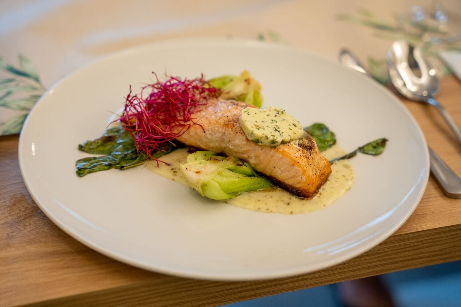 Une assiette contenant un morceau de saumon, des asperges et une sauce crémeuse.