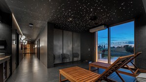 En moderne hotellobby med en lang gang, et loungeområde med træloungere og store vinduer med udsigt over det fri.
