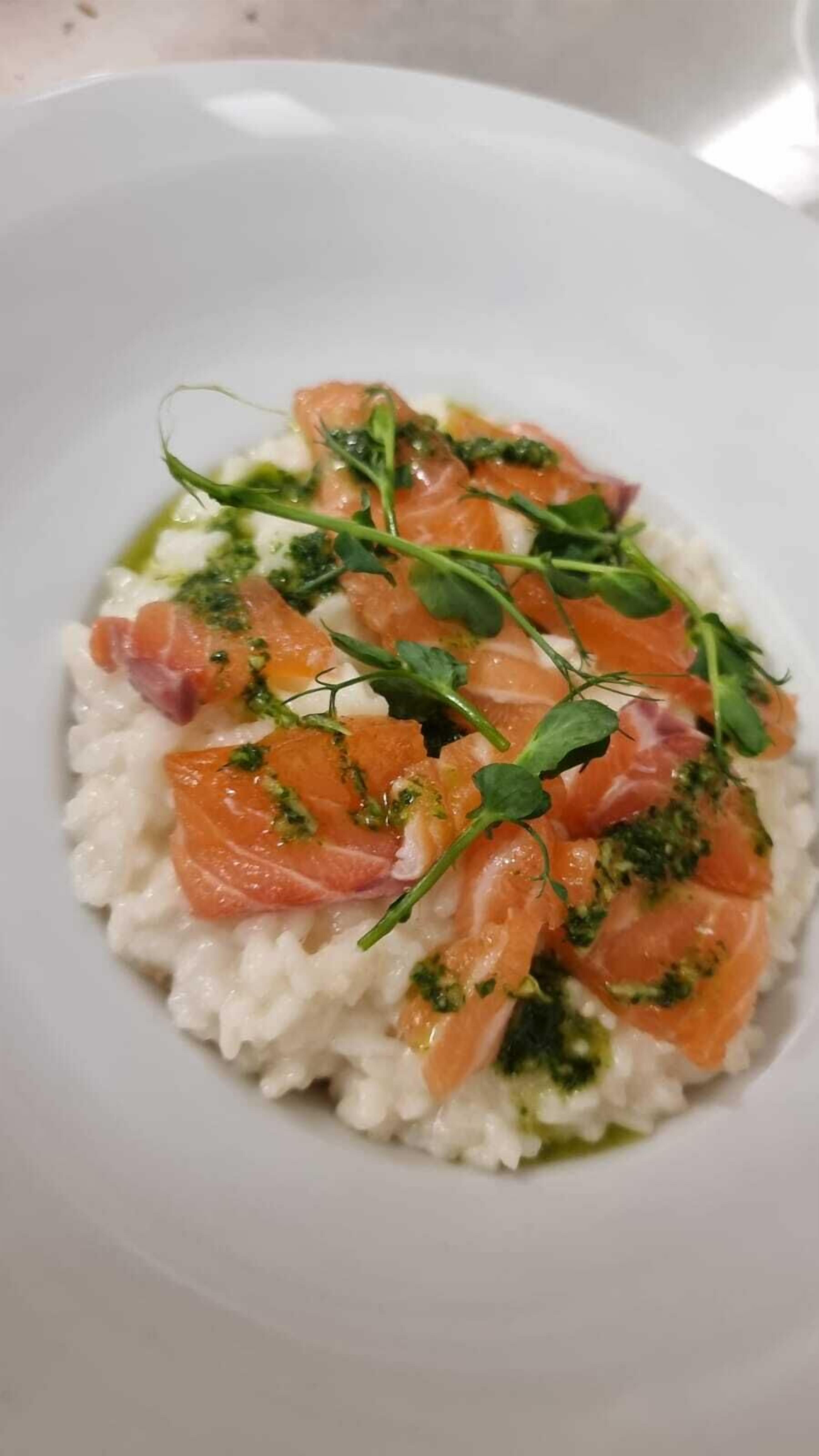 A plate of food with rice, salmon, and greens.