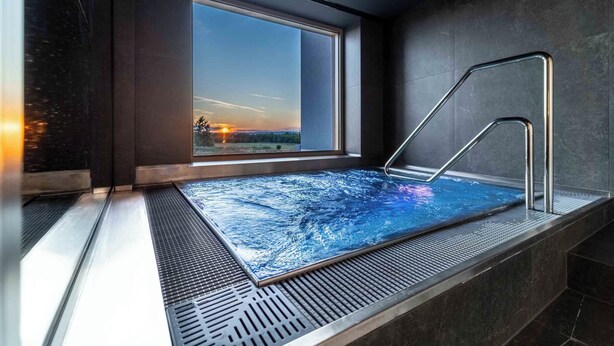 Et moderne spa med stort vindue, jacuzzi og metalstige.