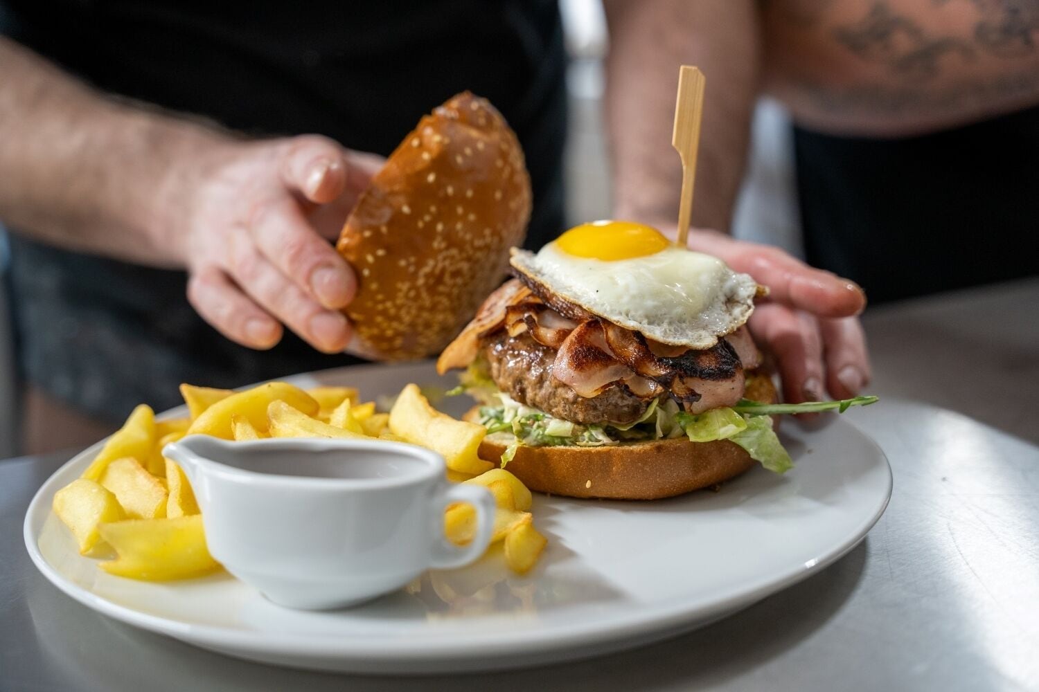 A plate with a burger, fries, and a small cup.