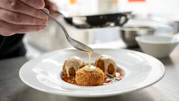 En tallrik med tre panerade köttbullar och en sås som hälls över dem.