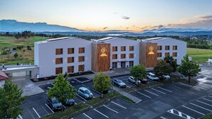 Et hotel med moderne design, parkeringsplads og udsigt over det omkringliggende landskab.