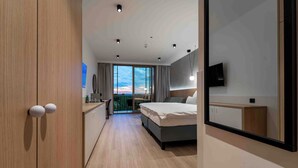 Et moderne hotelværelse med seng, skrivebord og stort vindue med udsigt til det fri.
