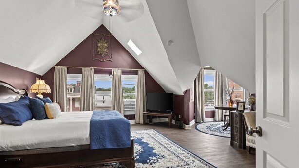 Ein geräumiges Schlafzimmer mit einem großen Bett, einem Fernseher und Blick ins Freie.